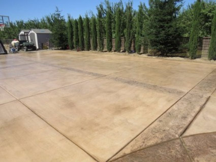 Large stamped concrete pad in front of a shed with colored concrete accents