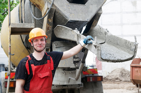 young concrete worker smiling next to cement truck
