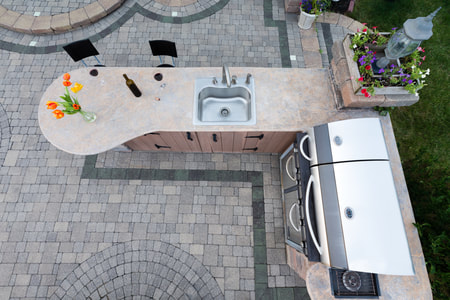 paved backyard patio with beautiful brick design surrounding inset barbecue and concrete counter top