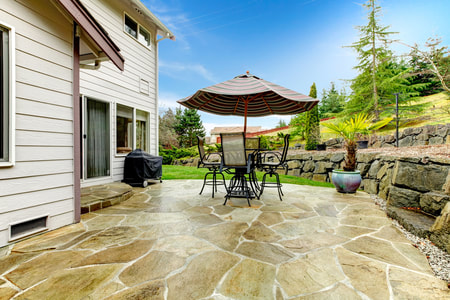 Backyard with shiny stone patio and rock retaining wall